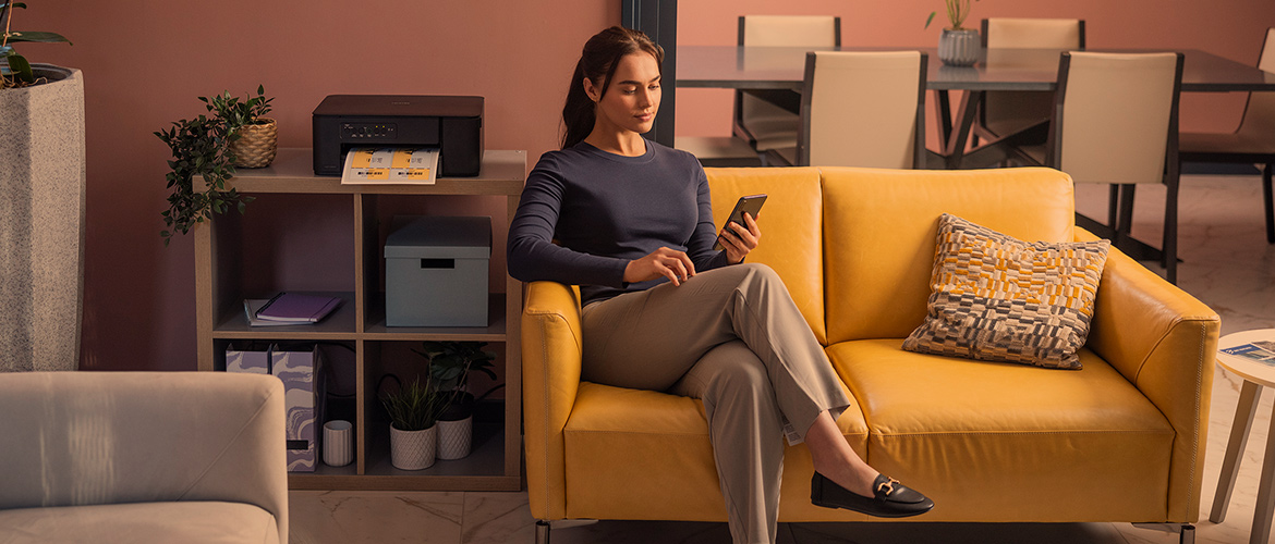 <p>Life Flows Better With Brother banner, for the For Home page. The image shows a person sat on the couch near their Brother UK printer. </p>