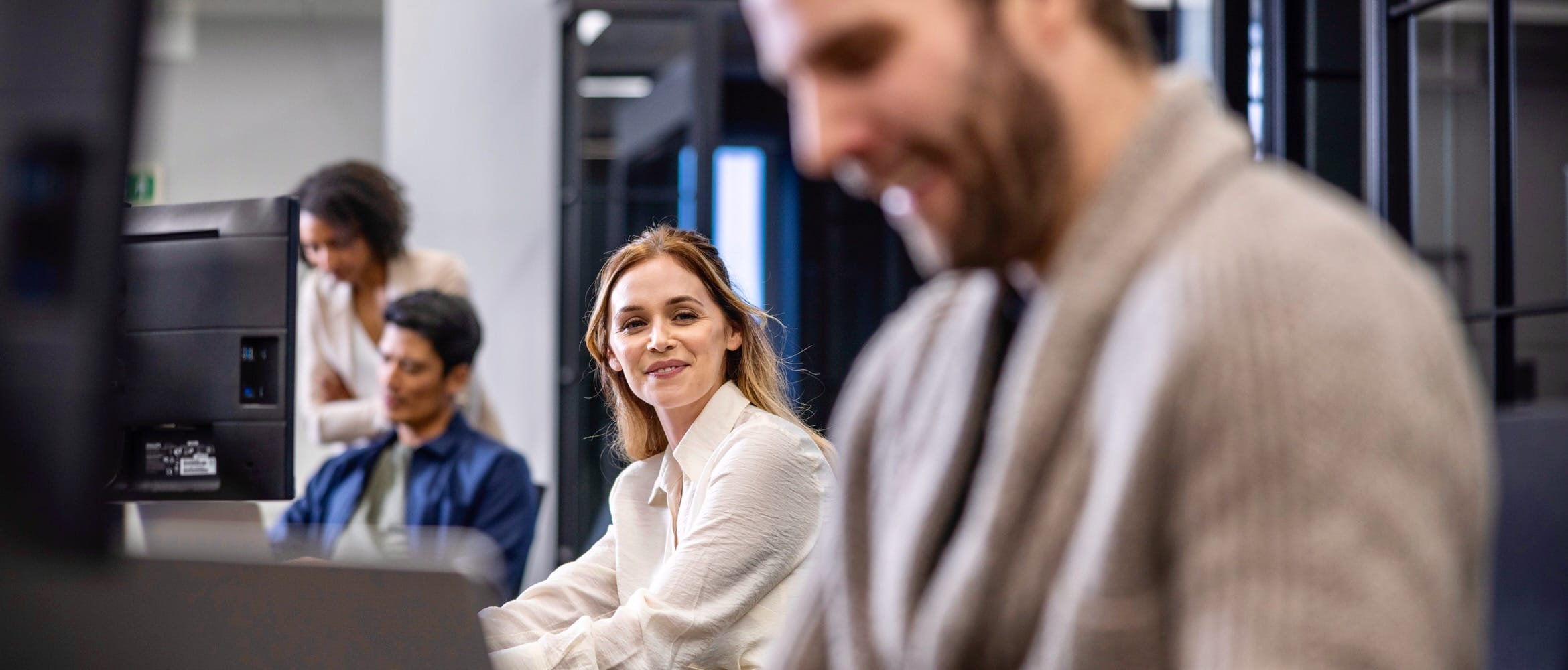 <p>Four IT team members working on desktop computers in an office environment</p>