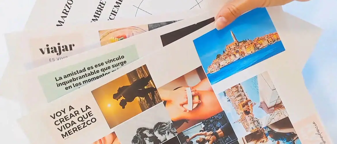 <p>A close-up of a woman's hand holding four pieces of paper that contain collages of pictures and snippets of text to form vision boards</p>