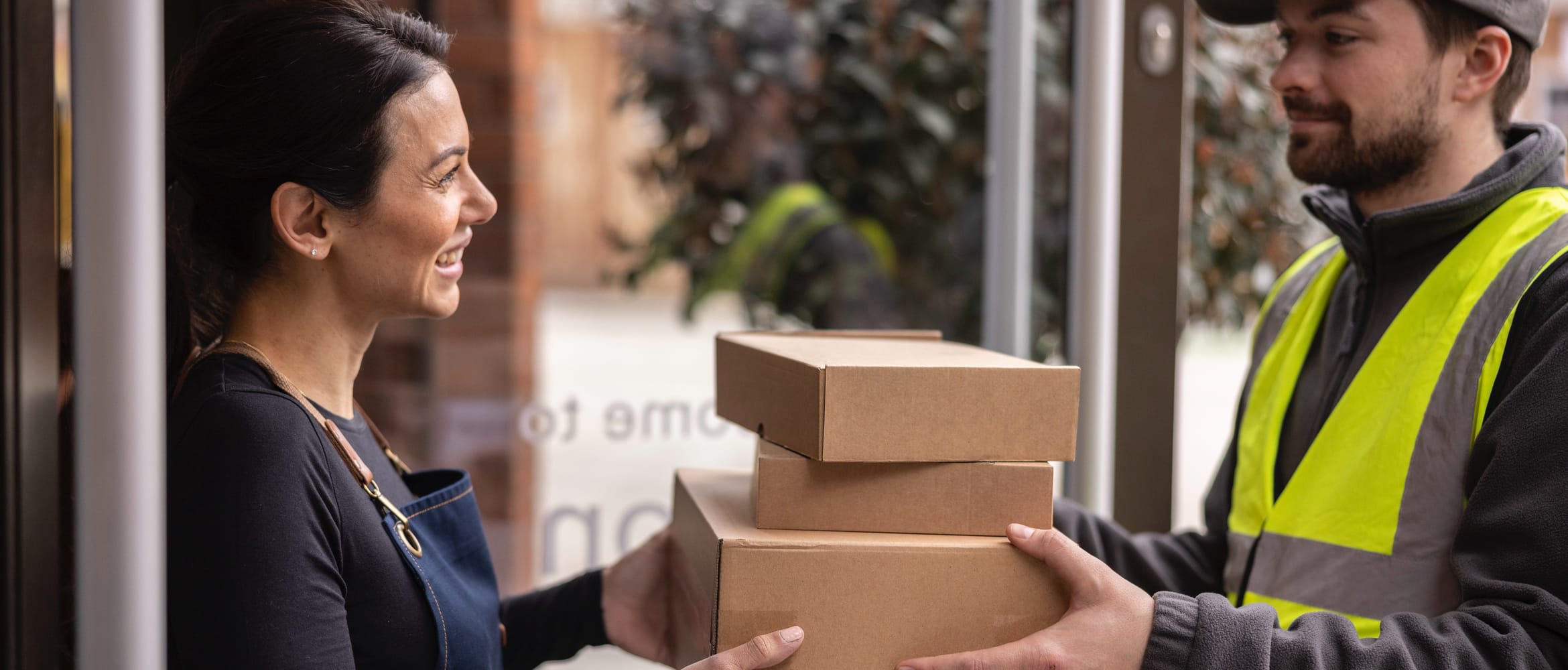 <p>A small business owner receiving boxed ink supplies from a delivery man wearing a hi-vis vest</p>