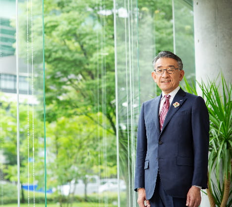 Kazufumi Ikeda - Director and President of Brother Industries Ltd Japan - is pictured in a business suit and tie against a green environmental background in this corporate portrait headshot